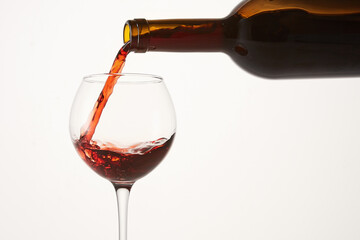 Round wave of pink wine flowing from bottleneck to glass.