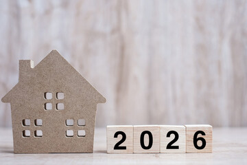 2026 Happy New Year with house model on table wooden background. Banking, real estate, investment, financial, savings and New Year Resolution concepts