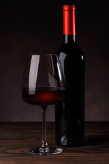 Wine glass filled with wine beside a bottle