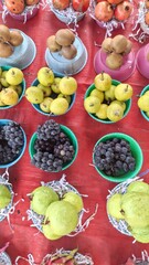 Colorful Assortment of Fresh Fruits in Bowls – Pears, Grapes, Kiwis, Pomegranates on Red Surface, Organic Produce, Healthy Eating, Market Stall, Natural Food Stock Photo