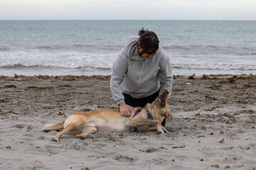Woman playing with her dog in the beach.