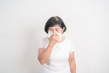 Elderly woman blowing her nose with tissue for concepts of Common Cold, Influenza, Flu, Hay, Fever, Covid 19, Respiratory Infection, Sinusitis, Allergic Rhinitis, Allergy, Medical and health care
