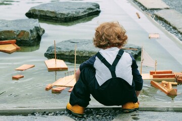 Niño jugando con barquito de madera