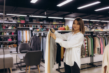 Young Woman Shopping in Boutique Store Surrounded by Clothes and Accessories
