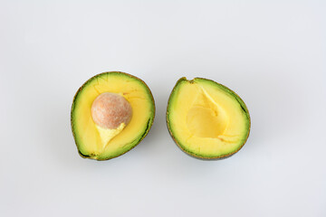 Avocado halves with seed, fresh and ripe, isolated on white