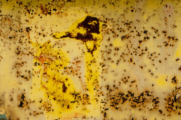 Rusty yellow metal surface with extensive corrosion and peeling paint on an old industrial door,...