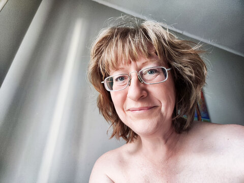 Middle-aged woman takes a morning selfie in her bedroom after waking up