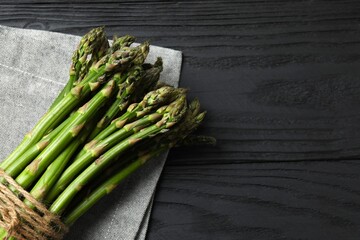 A bunch of freshly harvested asparagus spears are neatly arranged on a rustic wooden table
