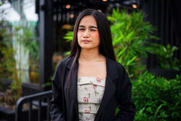 A playful young asian woman standing and winking at the camera, radiating charm and lighthearted energy in a fun and casual moment at a cafe