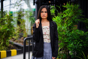 An unsure young asian woman with a furrowed brow and fist lifted upward, displaying a moment of confusion and hesitation at a cafe