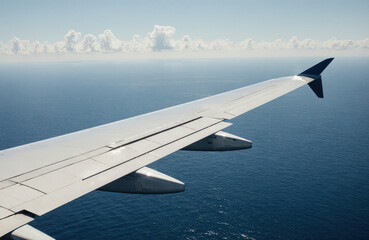Fototapeta premium Aerial view of an airplane wing flying over the ocean on a clear day