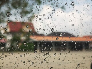 Rain drops on the window . Windshield on rainy days, visible outside the building.
(This orange roofed building is a place for monks called a temple in Buddhism.)