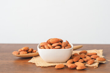 Almonds in white bowl on wooden table background