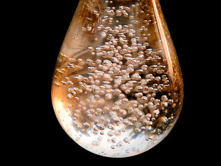 Abstract teardrop shape with trapped air bubbles against a stark black background