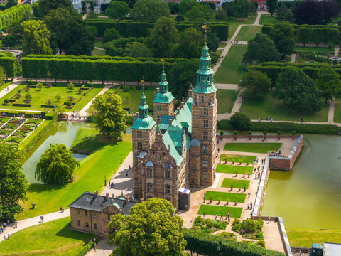 Aerial view of Rosenborg Castle in Copenhagen, Denmark, featuring green spires, Renaissance architecture, lush gardens, and symmetrical pathways.