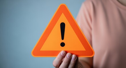 Person Holding an Orange Triangular Warning Sign with Exclamation Point, Hazard Awareness and Attention