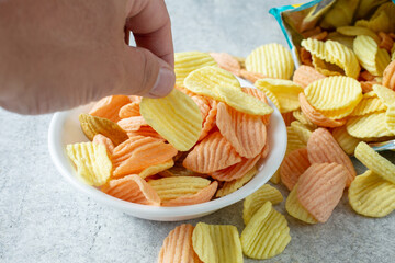 A view of a hand picking up a ridged vegetable chip.
