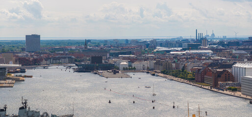 Fototapeta premium Aerial view of Copenhagen, Denmark, featuring the harbor, Amager Bakke waste to energy plant, Opera House, wind turbines, and a mix of urban architecture.