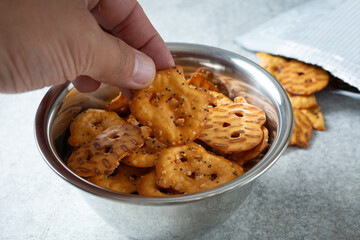 A view of a hand holding a gluten-free pretzel cracker.