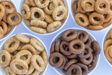 Freshly baked mini bagels on a dark background. Top view. Pretzels in the form of a ring close-up. Small bread circle biscuit. Bowls with different types of bagels.