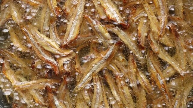 Frying dried anchovies fish in boiling oil. Top view shot