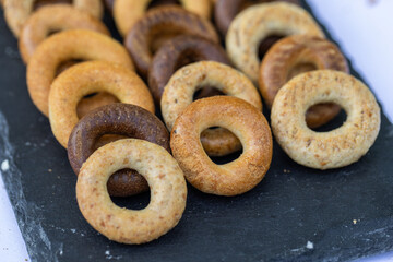 Freshly baked mini bagels on a dark background. Top view. Pretzels in the form of a ring close-up. Small bread circle biscuit. Bowls with different types of bagels.