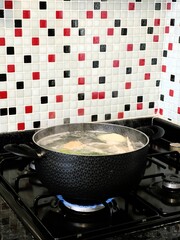 A pot on the stove with boiling chicken broth.