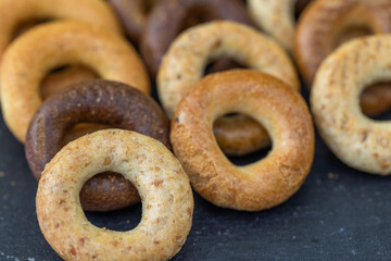 Freshly baked mini bagels on a dark background. Top view. Pretzels in the form of a ring close-up. Small bread circle biscuit. Bowls with different types of bagels.
