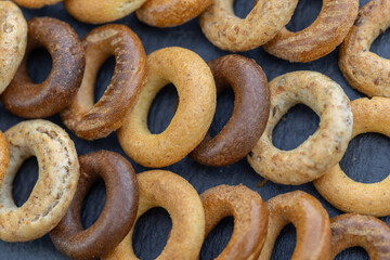 Freshly baked mini bagels on a dark background. Top view. Pretzels in the form of a ring close-up. Small bread circle biscuit. Bowls with different types of bagels.