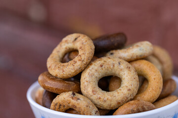 Freshly baked mini bagels on a dark background. Top view. Pretzels in the form of a ring close-up. Small bread circle biscuit. Bowls with different types of bagels.