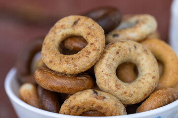 Freshly baked mini bagels on a dark background. Top view. Pretzels in the form of a ring close-up. Small bread circle biscuit. Bowls with different types of bagels.