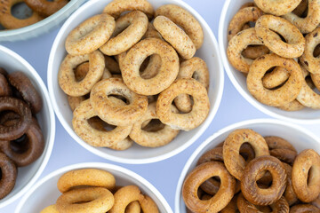 Freshly baked mini bagels on a dark background. Top view. Pretzels in the form of a ring close-up. Small bread circle biscuit. Bowls with different types of bagels.