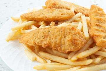 A closeup view of a plate of chicken tenders and french fries.
