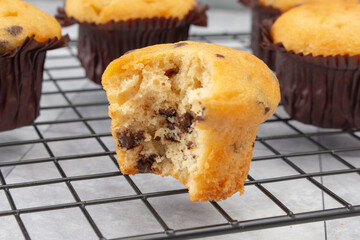 A closeup view of gluten-free chocolate chip mini muffins, with a bite mark.