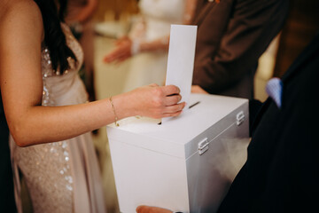 Dłonie wrzucające kopertę do pudełka