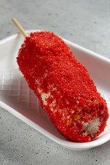 A view of elote, topped with flaming hot cheesy crunchy chips.
