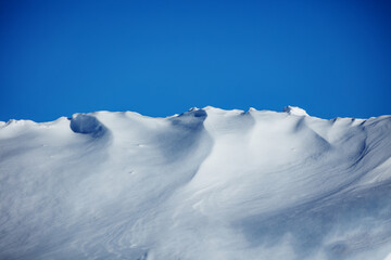 Wind-sculpted snowdrift ridge glistens under a deep blue sky