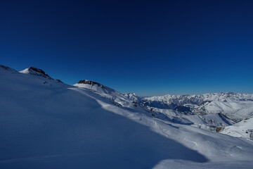 Snowy mountain alpine peaks and slopes under a deep blue sky