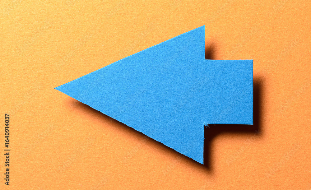 Poster blue cut out paper cardboard arrow direction sign with copy space for text on orange background, fla