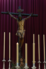 Sculpture inside a church of Jesus Christ crucified with candles around him