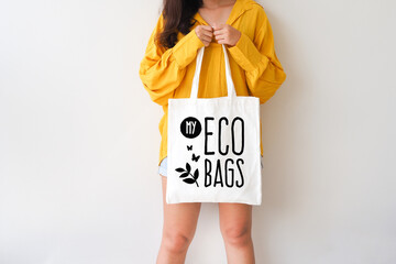 Woman holding canvas tote bag on white background. Reusable eco bag for shopping. Eco friendly...