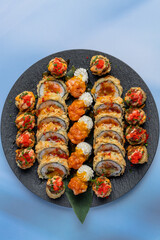 Tempura sushi roll on a black plate on a light background