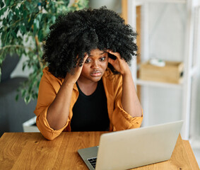 Portrait of a young woman girl worried surprised and stressed using laptop in office, or a...