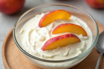 Creamy yogurt with fresh peach slices in a glass bowl  