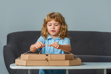 Little child looking at a pizzas box. Child is astonished by a big box with a huge pizzas, very...
