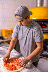 Process of making pizzas, pepperoni, salami. Raw pizza ingredients on table. Cook hand makes a...