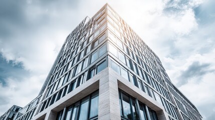 Fototapeta premium Modern Office Building Exterior with Glass Facade and Dramatic Sky, representing corporate architecture