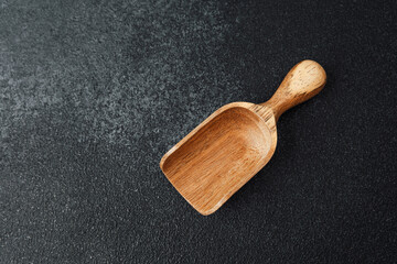 Wooden scoop on a dark textured surface ready for culinary use or crafting