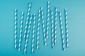 Blue striped paper straws on cyan background for party decoration or drinkware concept
