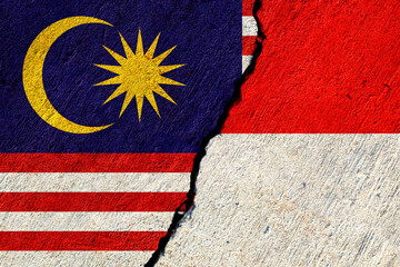 malaysia and indonesia flags painted on cracked concrete wall